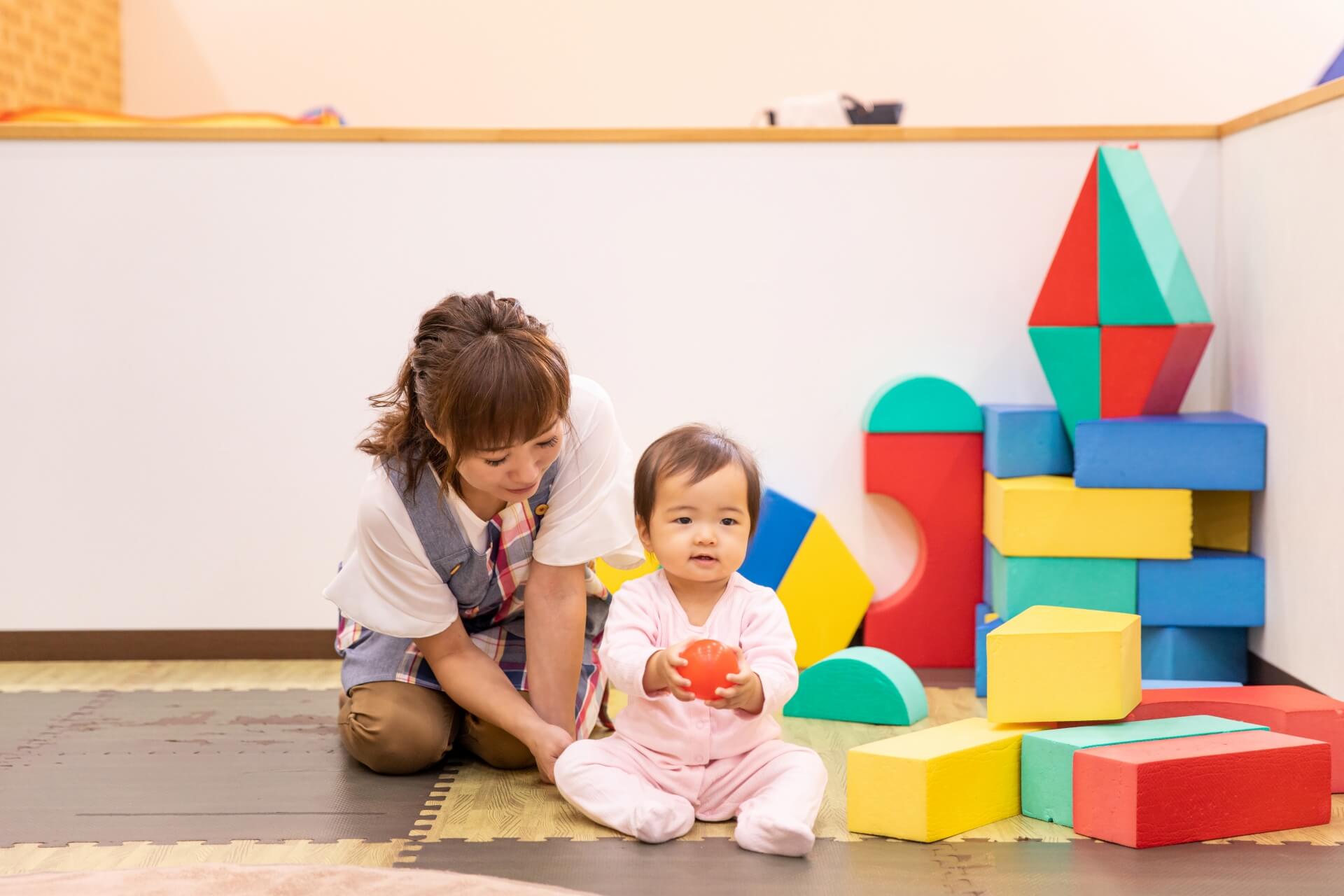 キッズルームの写真です。スタッフがお子様に寄り添い、一緒に遊んで待っている様子です。